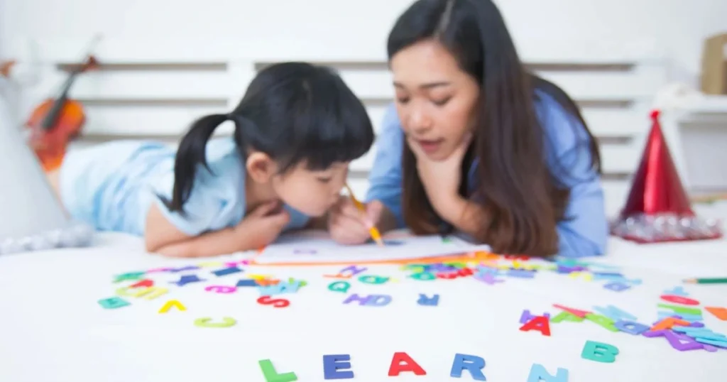 Preschool Classroom Activities with teacher helping child learn alphabet letters
